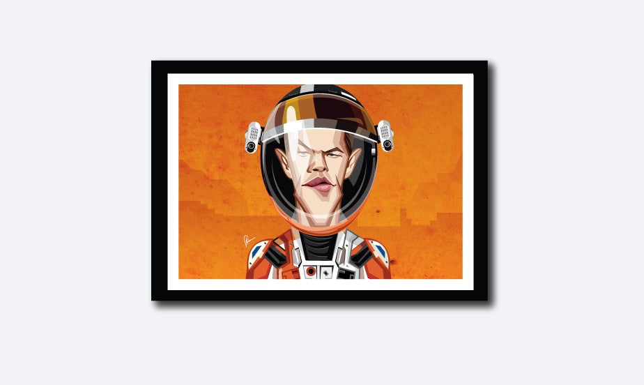 Matt Damon in his Caricature Art Form by Prasad Bhat. Image shows framed art poster of Martian avatar by Matt looking straight forward with his sleek eyes . He is wearing the astronaut's suit and helmet against a predominantly orange background.